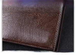 Macro shot of dark brown litchi grain leather and detailed edge finishing on a men's wallet