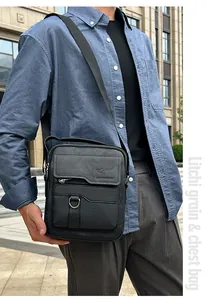 Close-up of a black litchi grain leather chest bag for men with metal zipper details
