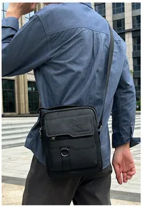 Outdoor view of a men's black crossbody bag with adjustable strap on a model