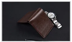 Close-up of brown litchi pattern leather wallet with business watch on black background