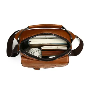 Brown leather crossbody bag for men showing spacious interior with books and umbrella