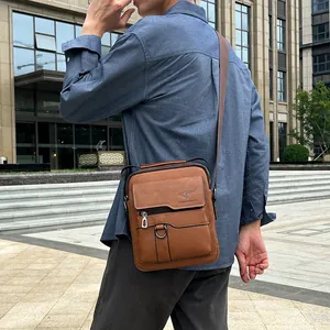 Men's brown leather crossbody bag with flap and kangaroo logo in an outdoor setting
