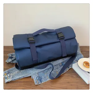 Detalle de bolsa de viaje azul marino con correas reforzadas y hebilla sobre mezclilla