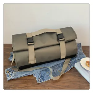 Detalle de bolsa de viaje gris en nailon impermeable con correas de hebilla caqui