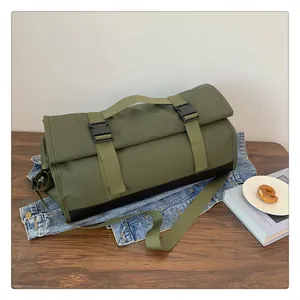 Detalle de bolsa de viaje verde oliva con cierre enrollable y hebillas sobre denim
