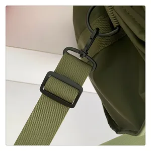 Detalle de tela de nailon verde militar con ganchos y anillos de metal negro mate