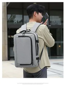 Grey business laptop backpack with side handle and USB port shown on male model back