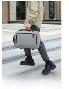 Man carrying a gray 16-inch laptop backpack on city stairs in a business setting