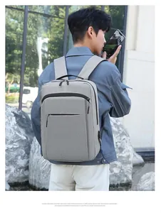 Modern grey laptop backpack with USB charging port shown on male model in outdoor setting