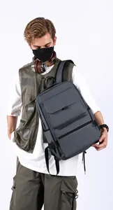Detail of gray waterproof travel backpack showing multi-pocket structure and front flap pocket