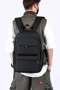 Rear view of model wearing a large black waterproof business backpack with multi-compartments