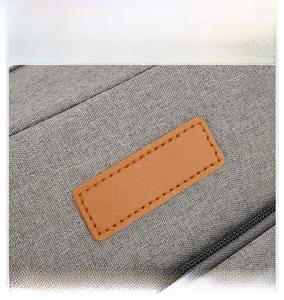 Détail du tissu en lin gris et de l'écusson en cuir marron sur le sac à déjeuner