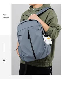 Detail view of fog blue casual backpack featuring a front zipper and astronaut plush charm
