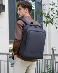 Side view of a man wearing a dark grey waterproof business laptop backpack in the street