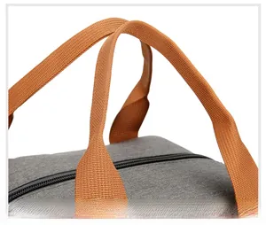 Détail de la poignée tressée orange et de la fermeture éclair du sac repas gris
