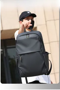 Detailed view of black water-resistant backpack showing carry handle and front zipper pocket