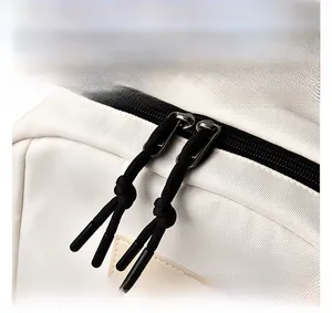 Détail des fermetures éclair à double sens avec cordons noirs sur sac à dos en toile crème