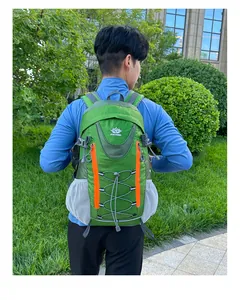 Détail d'un sac à dos de randonnée vert avec zips orange sur un mannequin en plein air