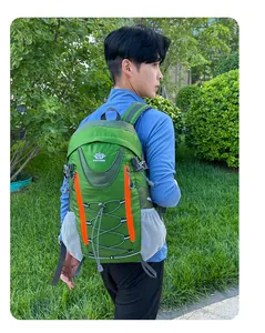 Sac à dos de voyage vert avec détails orange et poches latérales en filet porté par un homme