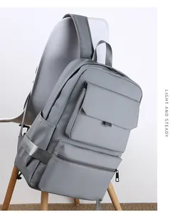 Detail of dark grey waterproof business backpack with pockets hanging on a white chair