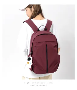Close-up of burgundy fashion backpack with astronaut charm and side pocket detail