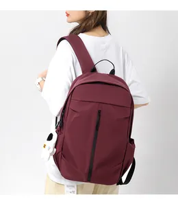 Detail of burgundy sports backpack with astronaut charm and vertical zip on model
