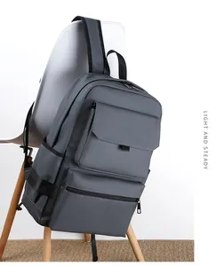 Dark grey business laptop backpack hanging on white chair in a modern office setup
