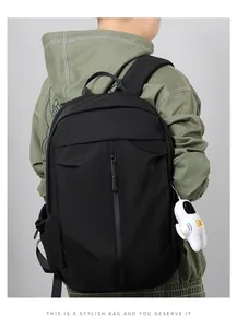 Detail of black waterproof backpack with front zipper and white astronaut plush charm