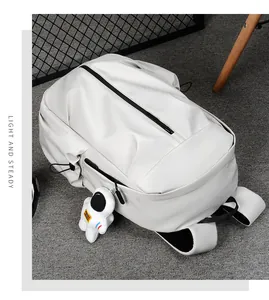 Detail of white minimalist backpack with smooth texture and astronaut plush charm