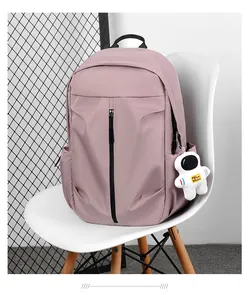 Detail of pink nylon backpack featuring vertical black zipper and astronaut keychain
