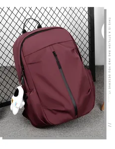Detail of burgundy casual backpack with vertical zipper and astronaut plush pendant charm