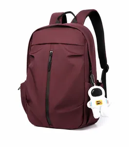 Side view of burgundy nylon sports backpack with white astronaut plush keychain detail