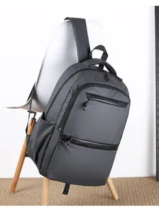 Detail of dark grey water-resistant business backpack with two front zipper pockets on a chair