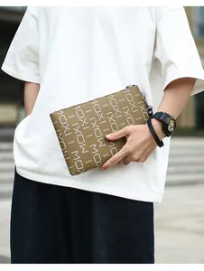 Close-up of brown letter print business clutch bag with metal zipper and wrist strap