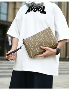 Close-up of khaki leather clutch featuring MOXI monogram and silver zipper hardware