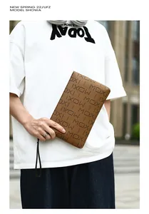 Detail of a brown men's clutch bag with letter prints and a thin black wrist strap
