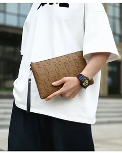 Close-up of brown leather clutch with MOXI letter print and wrist strap in city setting