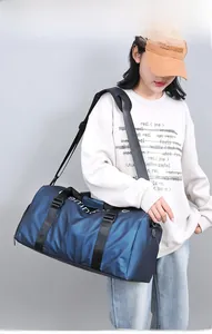 Sac de sport cylindrique bleu avec séparation sec-humide porté en bandoulière sur l'épaule