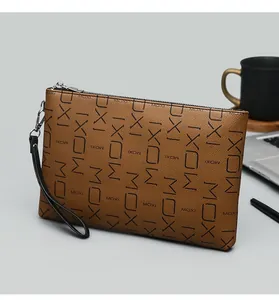 Close-up of brown textured leather clutch bag with letter print and metal zipper detail