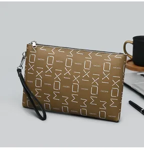 Detailed view of brown leather clutch bag with white MOXI lettering and business props