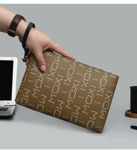 Detail of the brown leather clutch bag featuring all-over MOXI letter prints in an office setting