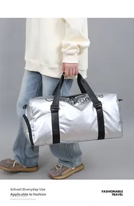 Détail du sac de voyage argenté métallisé avec poignées noires et compartiment zippé