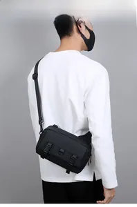Detail of adjustable nylon strap and plastic buckles on a black tactical crossbody bag