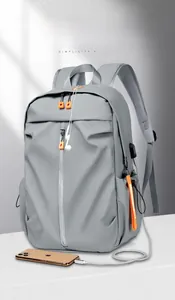 Detail of grey travel backpack showing external USB charging port connected to a phone