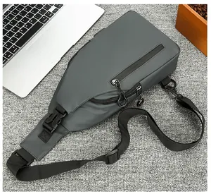 Detalle de bandolera gris impermeable con puerto USB sobre una alfombra con textura