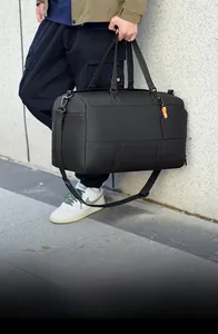 Close-up of a black matte travel bag with orange details and adjustable shoulder strap
