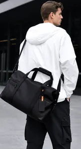 Close-up of black waterproof travel bag with reinforced handles and orange buckle detail