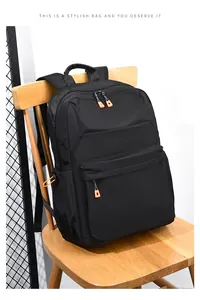 Dettaglio dello zaino in nylon nero con cerniere arancioni su una sedia in legno