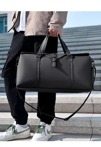 Close-up of a black waterproof travel bag with reinforced handles and adjustable shoulder strap