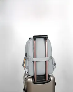 Grey travel backpack detail showing luggage strap secured to a gold suitcase handle
